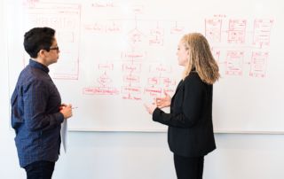 people standing in front of whiteboard with strategy brainstorm
